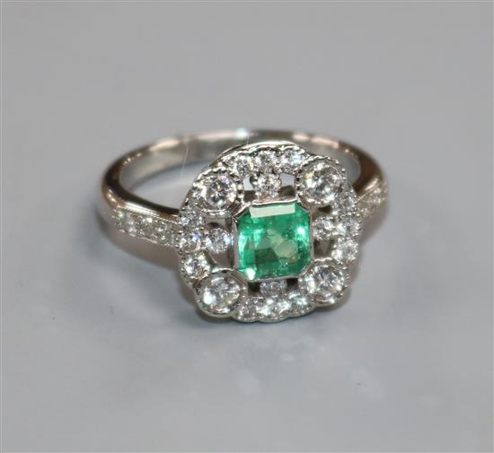 An Art Deco style white gold, emerald and diamond cluster ring, size M.
